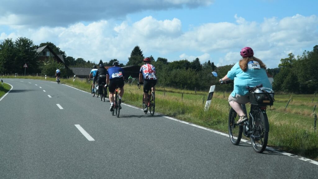 Teilnehmende der Großen Weserrunde fahren auf einer Landstraße durch die Landschaft des Weserberglands.